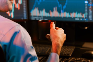 Neon Modern Ofis 'teki bulanık ekranda gerçek zamanlı olarak pazar stoku grafik verilerine odaklanmış kahve fincanı tutan kırpılmış genç tüccar. Finansal değişimi analiz etme kavramı. Toplayıcı.
