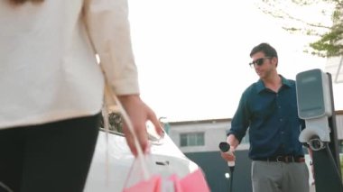 Açık şehir alışveriş merkezinin otoparkındaki şarj istasyonundan çift elektrikli araba aküsünü şarj ediyor. Enerji sürdürülebilir kentsel seyahat yaşam tarzı için şarj edilebilir EV araba