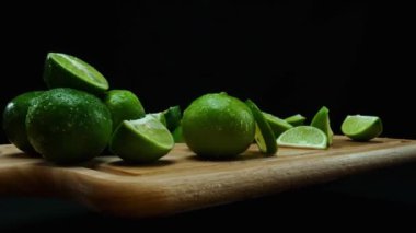 Yakın plan, canlı bir dilim taze kireç kırsal bir ahşap kesme tahtasının üzerinde duruyor. Tazelik ve canlılık yayıyor. Kesme tahtasına konmuş yeşil limon diliminin yarı saydam zarları. Geliştirilebilir.
