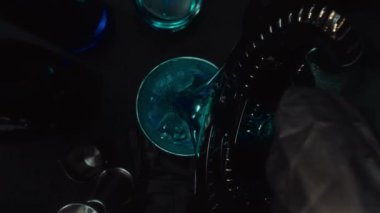 Mavi Hawaii kokteyli servis eden bir barmenin yukarıdan aşağıya bakışıyla makrografi. Siyah arkaplanlı bir ananas dilimiyle süslenmiş. Yakın çekim sıvı hareketini yakalar. Geliştirilebilir.