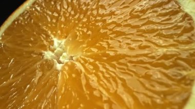 Portakal diliminin bir makrografi görüntüsü, parlak, izole edilmiş bir arkaplan üzerine yerleştirilmiş, narenciye cazibesinin görsel bir başyapıtı olarak gözler önüne seriliyor. Siyah arkaplanlı bir dilim portakal. Geliştirilebilir.