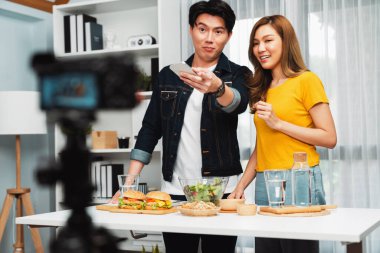 Aşçılar, sosyal medya yemek programı kanalı canlı yayın menü yemeği salatası, kepekli çörek ve video kameradan hamburger kaydı için telefonda yorum okuyorlar. İnfobahn.