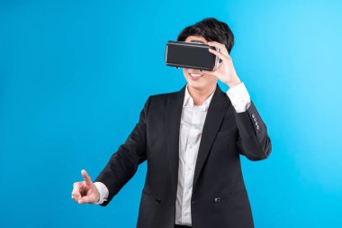 Asyalı işadamı, sanal gerçeklik mavi telif uzayı yenilik teknolojisini analiz eden gelecekçi metaevrendeki iş dünyası raporuna dokunarak ekranı titizlikle inceliyor. Entrika.