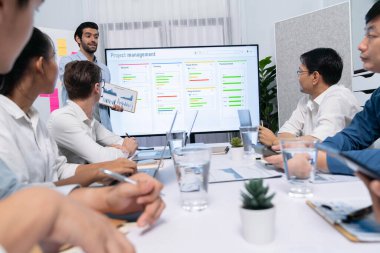 Proje yöneticisi monitörde proje yönetimi yazılım görüntülemesi, proje görevinin ilerlemesini izlemek ve toplantı masasında program planı yapmak suretiyle ekiple iletişim kurar ve işbirliği yapar. Tedbirli