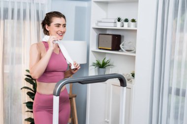Spor ve atletik bir kadın, evdeki fiziğe ve sağlıklı spor yaşam tarzına uygun vücut egzersizi sırasında koşu bandında koşuyor. Gaiety evde egzersiz eğitimi.