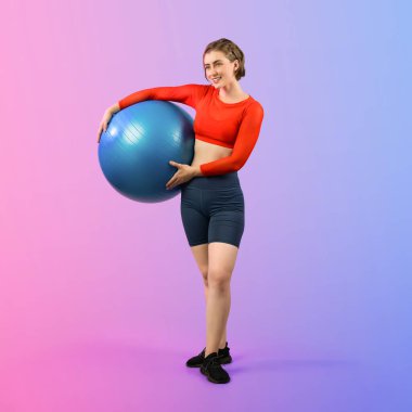 Vücut uzunluğunun tamamı atletik ve sportif genç bir bayanın izole edilmiş arka planda duran bir duruşta topa egzersiz yapmasıyla geçiyor. Sağlıklı aktif ve vücut bakımı yaşam tarzı.