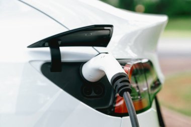 Temiz ve sürdürülebilir enerji kullanarak şarj olmak için EV şarj cihazına EV şarj cihazı takıldı. Doğal koruma ve çevre dostu araba yolculuğu konsepti. Yükselt