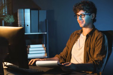 Genç işadamı, Neon Light Modern Ofis 'teki yeni proje surround çalışma masası için kağıt üzerinde tasarım düşünüyor. E-posta ile hediye göndermeden önce not defterine yeni bir iş düşünüyorum. Toplayıcı.