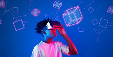 Geometrik şekillerde süzülürken mavi arka planda duran zeki çocuk. Afrikalı bir adam oyun oynuyor, VR gözlük takıyor ve sıradan bir gömlek giyiyor. Gelişmiş gerçeklik teknolojisi yenilik kavramı. Yaratıcılık.