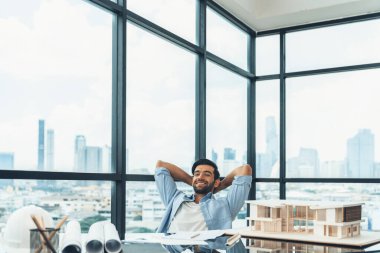 Modern ofis binasında otururken rahatlamış genç mimar mühendisinin tasarım ve dinlenme portresi. Erkek işçi ya da yönetici ara verir, bitirme projesinin ardından el ele tutuşur. İzleme