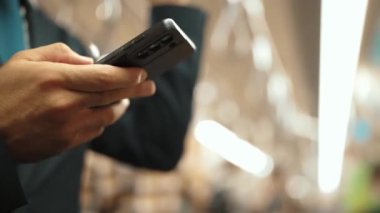 İş adamının elleri trende insanlarla çevriliyken telefona bakarken yakın çekim. Kafkas proje yöneticisi e-postaları kontrol ediyor, arka planı bulanık pazarlama stratejisi planlıyor. Sevinçli..