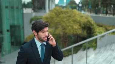 Gülümseyen yakışıklı iş adamı, parkın merdivenlerinde yürürken aynı zamanda işletme müdürünü arıyor. Yatırımcı işe giderken meslektaşıyla konuşuyor. Sevinçli..