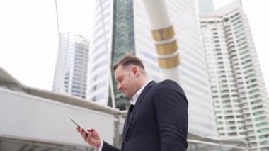 Kafkasyalı iş adamı şehir merkezinde dururken cep telefonlarını kontrol ediyor ve pazarlama ekibinden satış raporlarını inceliyor. Yetenekli bir yönetici cep telefonu üzerinde çalışıyor ve veri analizine bakıyor. Urbane.