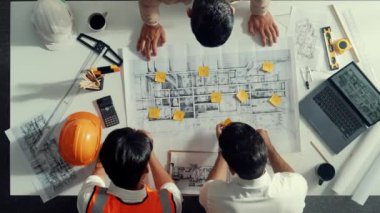 Akıllı mimar mühendis takımının yukarıdan aşağıya bakan ve bina inşaatı hakkında tartışan görüntüsü. Farklı insanlardan oluşan bir grup plan ve tasarım için birlikte çalışıyorlar. Hizalama.