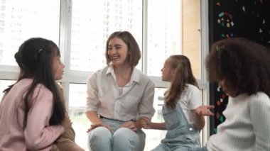 Öğretmen ve çeşitli öğrenciler sınıfta el ele tutuşuyorlar. Genç eğitmen ve çok kültürlü çocuklar tezahürat yapıyor ve teşvik ediyor. Birlik, sevgi, işbirliği, birlikte çalışma. Etkinlik.