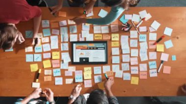 Ux Ui tasarımı kullanılarak dijital program ve yazıları tartışan ve gösteren geliştirici ekibin hava görüntüsü. İş dünyasına tepeden bakan insanlar telefon ve bilgisayar için kablo prototipi geliştiriyorlar. Sempozyum.