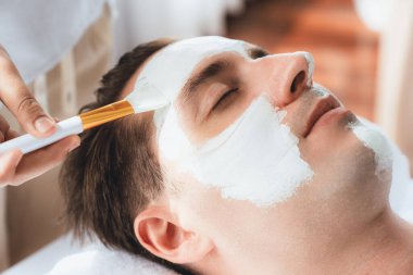 Kaplıca salonunun sakin atmosferi, insan müşterisi modern gün ışığında lüks yüz kremi masajıyla kendini yenileme zevkine kapılıyor. Yüz bakımı ve güzellik konsepti. Sessiz.