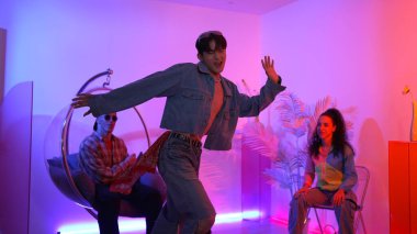 Çok kültürlü bir arkadaş kürsüde otururken Asyalı yetenekli bir dansçı modern müziğe geçiyor. Profesyonel dansçı, hipster takımı tezahürat yaparken ve desteklerken enerjik adımlar atıyor. Mutluluk.