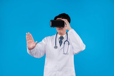 Stetoskoplu bir doktor, VR kulaklık kullanarak mavi zemin üzerinde 3 boyutlu hologram sağlık uygulaması ve tıbbi teknolojinin yenilikçi poster materyali tasarımı kullanıyor. Entrika.