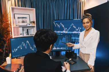 PC ekranlarında dinamik borsa istatistiklerini tartışan iş ortaklarının kağıt üzerinde not alması, para birimi grafiğindeki yüksek ya da düşük nokta ile gece neon çağındaki modern ofis karşılaştırıldığında. İnfobahn.