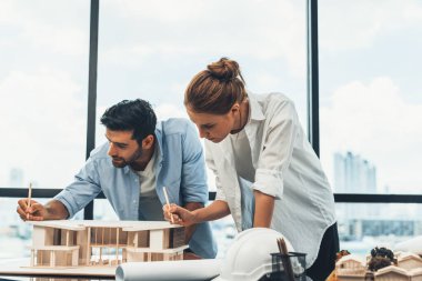 Akıllı beyaz mimar mühendis takımı ev modelini ölçmek için birlikte çalışıyor. Bir grup profesyonel iç mimar tasarım inşaatı hakkında fikir paylaşımı ve beyin fırtınası yapıyor. İzleme.