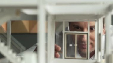 Kafkasyalı mimar mühendisinin yakın çekimi ev inşaatını denetlemek ve bina malzemelerini kontrol etmek. Proje yöneticisi modele dikkatlice bakarken kalemi işaret ediyor. Yönlendirici.