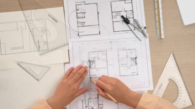 Akıllı mimar ya da akıllı mühendisin ölçüm aracı ve kalem el kullanarak mimari ofisindeki inşaat isabet planı üzerine detaylı bir yazı yazışının videosu. Eline odaklan. - Yakın çekim. Tanımlama.