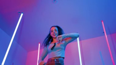 Latin dansçıların kameraya bakıp şehrin pop müziğiyle dans ettiği düşük açılı kamera. Profesyonel çekici hipster, mor veya neon ışıklı hip hop şarkısına geçiyor. Şık bir kumaş. Mutluluk.