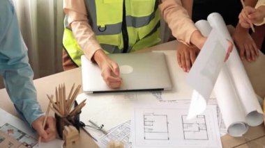 Mimari döküman, ölçüm araçları ve ahşap blokların modern ofiste etrafa saçıldığı masa üzerine planlar yapma konusunda akıllı mimar ve güvenlik mühendisi tartışması. - Yakın çekim. Tanımlama.