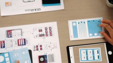 Mobil uygulama için kullanıcı arayüzü prototipini ofis çalışanlarına sunan harika bir şirket çalışanı. UX UI tasarımcısı kağıt üzerinde simge tasarımının işlevini açıklıyor. Sinerjik