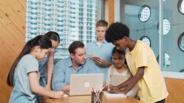 Akıllı robotlar sınıfta dizüstü bilgisayar ekranını işaret ederken, beyaz bir öğretmen yorum yapıyor ya da öğrencilere tavsiye veriyor. Öğretmen bilgisayar kullanırken çeşitli öğrencilerin ders verirken not alması. Öğretim