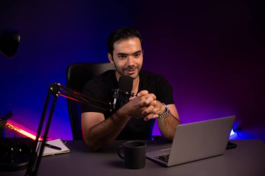 Yayıncı, fanclub dinleyicisiyle mikrofon kullanarak konuşuyor. Mor neon ışıklı modern stüdyoda yaratıcı olumlu düşünce konseptiyle canlı yayında finansal sorunları tartışıyor. Tahmin et..