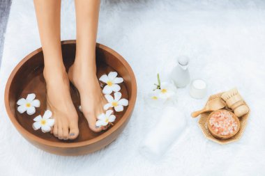Panorama üstteki kadın lüks spa salonunda mutlu bir ayak masajı yaparken, masör de hafif gündüz atmosfer tesisinde veya otel ayak spasında refleksoloji terapisi uyguluyor. Sessiz.