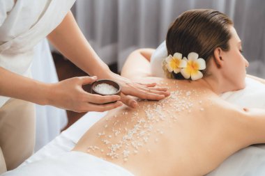 Lüks spa salonlarında sıcak mum ışığında cilt bakımı yaptıran kadın müşteri. Sağlık Spa vücut fırçasında tuz temizleme güzellik tedavisi. Sessiz.