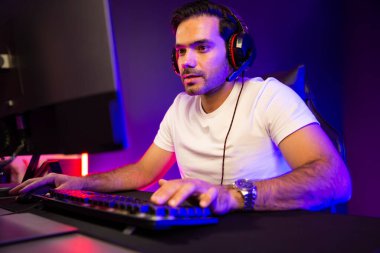 Akıllı oyun kurucusu, dijital neon ışıklandırma stüdyosundaki sosyal medya uygulamasında başkalarıyla iletişim kurmak için kulaklık ve mikrofon kullanan takım üyeleriyle konuşuyor. Tahmin et..