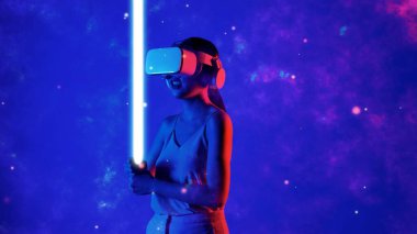 VR transferini kullanan kadın oyuncu metaevren eskrim oyununa sahip kılıç lazerli fantezi oyun alanına bakıyor mavi duman meta-3 boyutlu siber uzay dünyasını aydınlatıyor. Halüsinasyon.