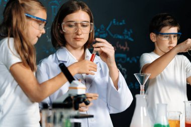 Laboratuvarda çalışan öğretmen, güvenlik gözlüğü takıyor, STEM sınıfında kimya bilimi üzerine deney yapıyor. Öğrenci komedisi tüpte sıvı deneyi yapar. Etkinlik.