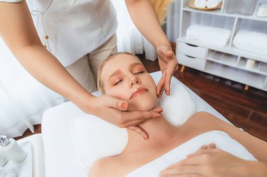 Kafkasyalı kadın stres önleyici kafa masajından ve lüks tatil beldesi ya da otel spa salonundaki modern ışık ortamında yüz güzelliği eğlencelerini şımartmaktan hoşlanıyor. Sessiz.