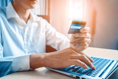 Genç adam, laptop bilgisayar başvurusu ya da web sitesinde online alışveriş yapmak için kredi kartı kullanıyor. E-ticaret ve online alışveriş konsepti. uds