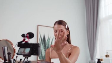 Sosyal medya için güzellik ve kozmetik video içeriği hazırlayan genç bir kadın. Güzellik blogcusu kameraya gülümserken seyircilere ve takipçilere güzellik bakımını gösteriyor. Düzenle
