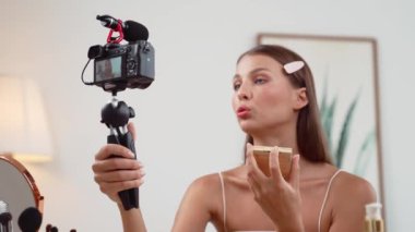 Sosyal medya için güzellik ve kozmetik video içeriği hazırlayan genç bir kadın. Güzellik blogcusu kameraya gülümserken seyircilere ve takipçilere güzellik bakımını gösteriyor. Düzenle