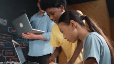 Çeşitli öğrencilerden oluşan bir grup program yazmak için birlikte çalışıyor. Öğretmenler BTMM dersindeki hata noktasını açıklarken çok kültürlü çocukların kodlaması ya da programlaması. Öğretim