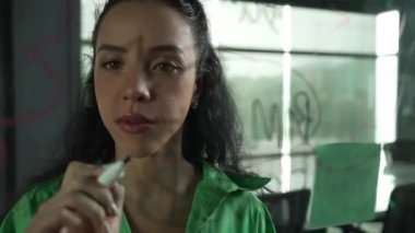 Zeki, profesyonel İspanyol iş kadınının portresi renkli yapışkan notlarla cam tahtaya pazarlama fikirleri yazıyor. Genç yönetici, analiz iş planının zihin haritasını çiziyor. - Yakın çekim. Yönlendirici.