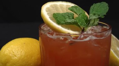 Makrografi, bir dilim limon ve taze naneyle süslenmiş Tekila Sunrise kokteyli, dramatik bir siyah arkaplan üzerine kurulmuş. Yakın çekim kokteylin canlı renklerini yakalar. Geliştirilebilir.