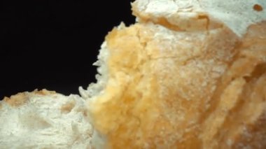 Koyu arkaplanda yırtık taze ekmek parçalarını yakın plan çek. Tahta tepsiye konmuş Fres ekmeklerinin makro fotoğrafları. Yakınlaştır ve kamera hareketini döndür. Gurme ve fırın konsepti. Pabulum.