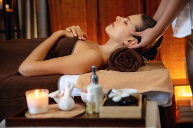 Beyaz kadın stres önleyici kafa masajı yapmaktan ve lüks otel veya otelde sıcak mum ışığında yüz güzelliği eğlencesi yapmaktan zevk alıyor. Sessiz.