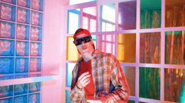 Kafkas dansçısı dans ederken çeşitli arkadaşları gece kulübünde neon ışıkta ayak seslerine bakıyor. Çoklu etnik kökenli hipsterin serbest stil müziğe geçişi ve mutlu bir adamın kameraya bakışıyla. Mutluluk.