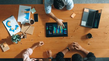 İş adamının üst düzey görüşü, bir grup akıllı yatırımcıya finansal grafik sunuyor. Profesyonel erkek lider grafiği analiz eder ve pazarlama fikrini toplantı masasında tablet kullanarak açıklar. Cemaat.