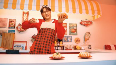 Profesyonel Asyalı restoran işçisi yemek hazırlar ve yemek barının arkasında durur. Kırmızı gömlekli ve kırmızı önlüklü mutlu garson kameraya bakarken serbest stil müziğe geçiyor. Çılgın dans. Mutluluk.