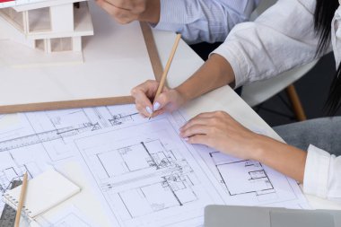 Profesyonel mühendis ev modelini tartartarken, yetenekli tasarımcı da planına yazar. Birlikte çalışmak, işbirliği, işbirliği. Yaratıcı tasarım ve takım çalışması konsepti. Üst Manzara. Tertemiz..